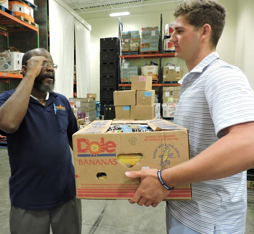  Volunteer Sam Koby of Bayside Academy, right, gets instructions from Ron Henderson, the reclamation coordinator for Feeding the Gulf Coast, on unloading an incoming box of groceries that will be distributed to the needy in Mobile, Alabama . (AHSAA photo) 